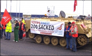 Striking Tesco drivers bring a tank to the picket line with a Unite banner attached 