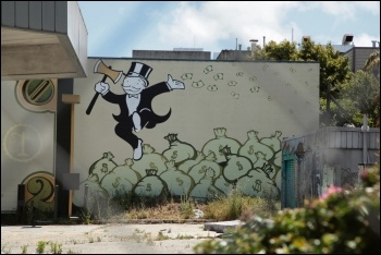 Monopoly man with axe dancing on money bags, 1% super-rich austerity inequality, photo torbakhopper (Creative Commons)