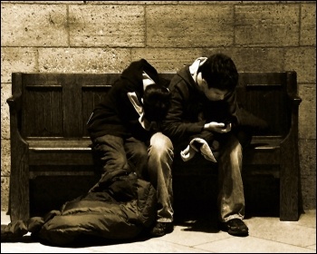 Young woman and man wait on a bench with a sleeping bag at night, photo by Tony Fischer (Creative Commons)