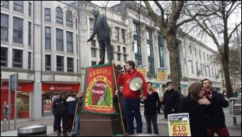 Jaime Davies speaking next to a statue of Nye Bevan