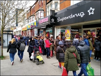 A queue out the door of a pharmacy in East Ham, London, March 2020, photo by Dave Carr