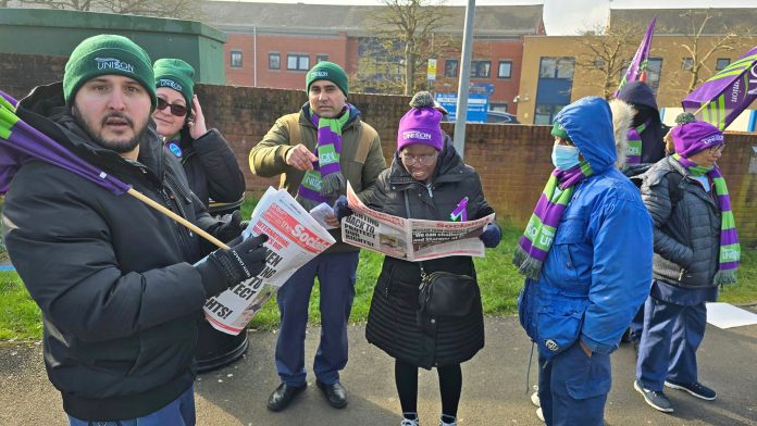 Striking health workers reading the Socialist on the picket line. Photo: John GIllman